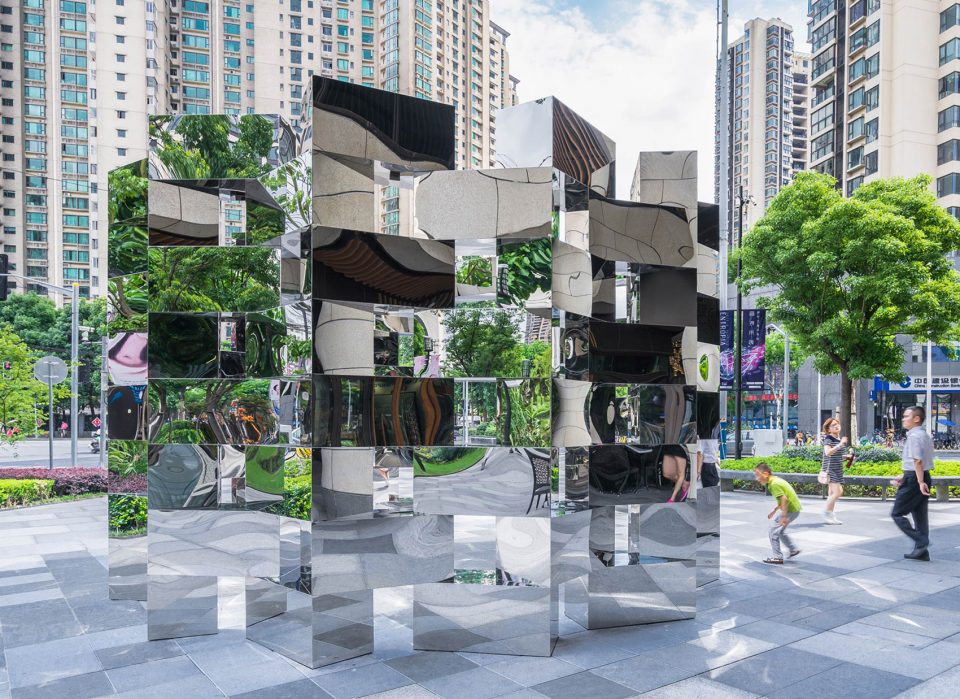 The full ring of staggered mirror cubes of Ring • Chain with pedestrians walking past in Shanghai