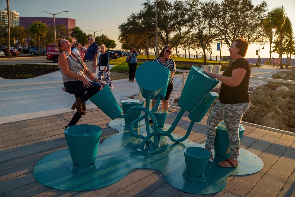 A group of people playing Drum Coral together at golden hour on a waterfront deck in Sarasota