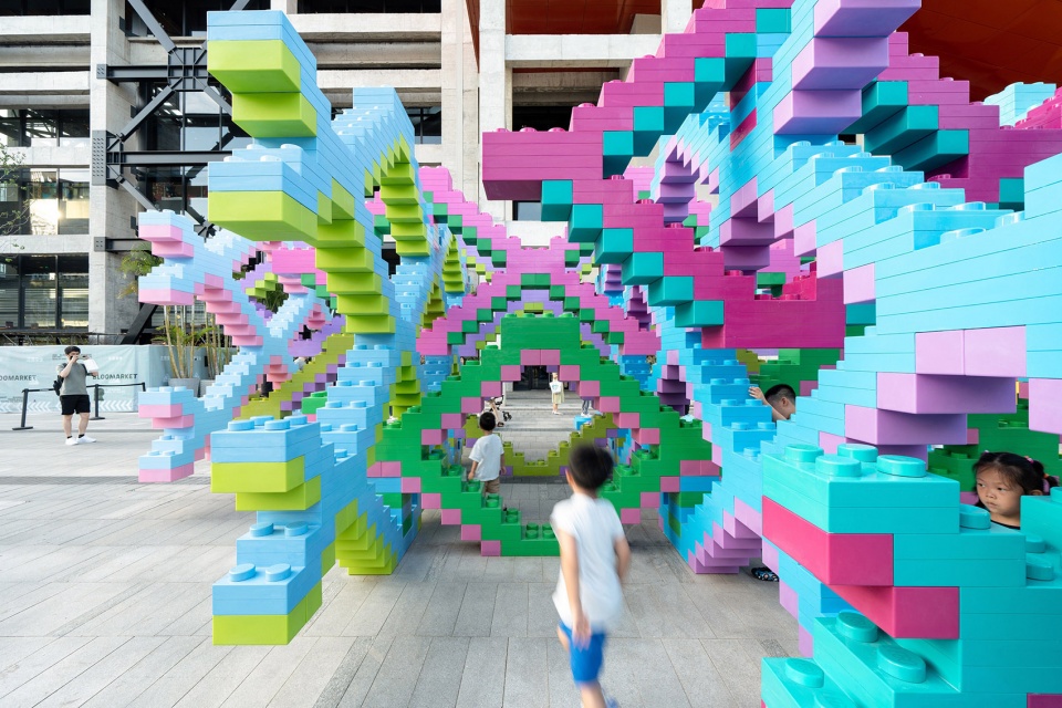 Children walking through a colorful climbable installation made of oversized toy bricks in a Shanghai plaza, Woven Playground by Saxing Jizi Design