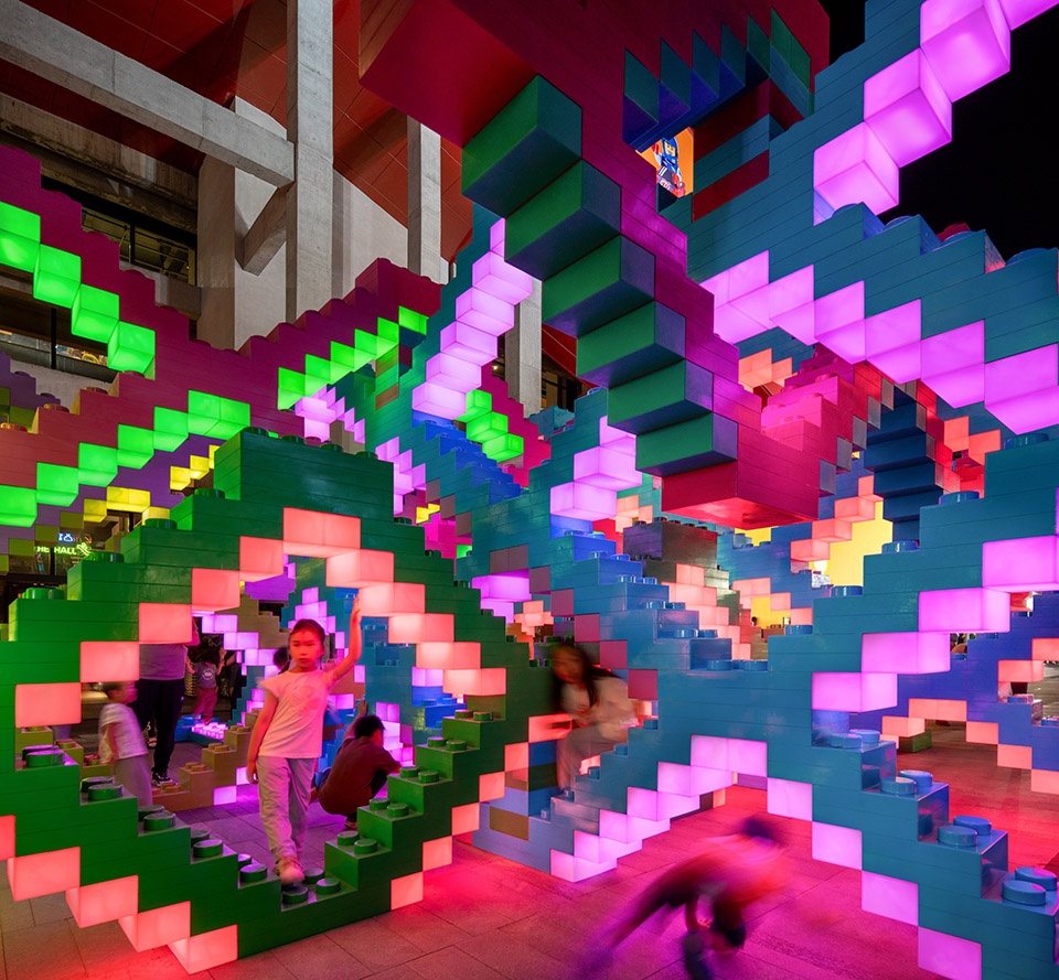Woven Playground installation at night with illuminated oversized bricks in pink, green, and blue, Shanghai